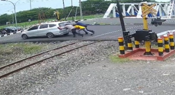 polisi-mendorong-mobil-yang-mogok-di-rel-kereta-semarang